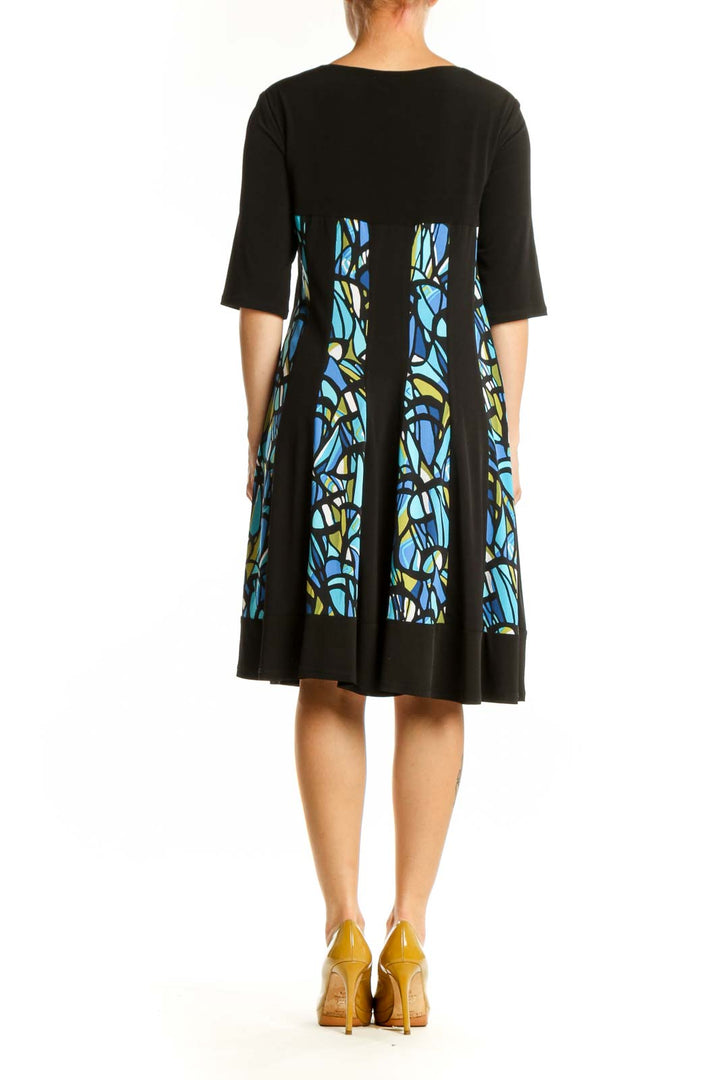 Black A-line dress with blue and yellow stained glass pattern panels, three-quarter sleeves, back view