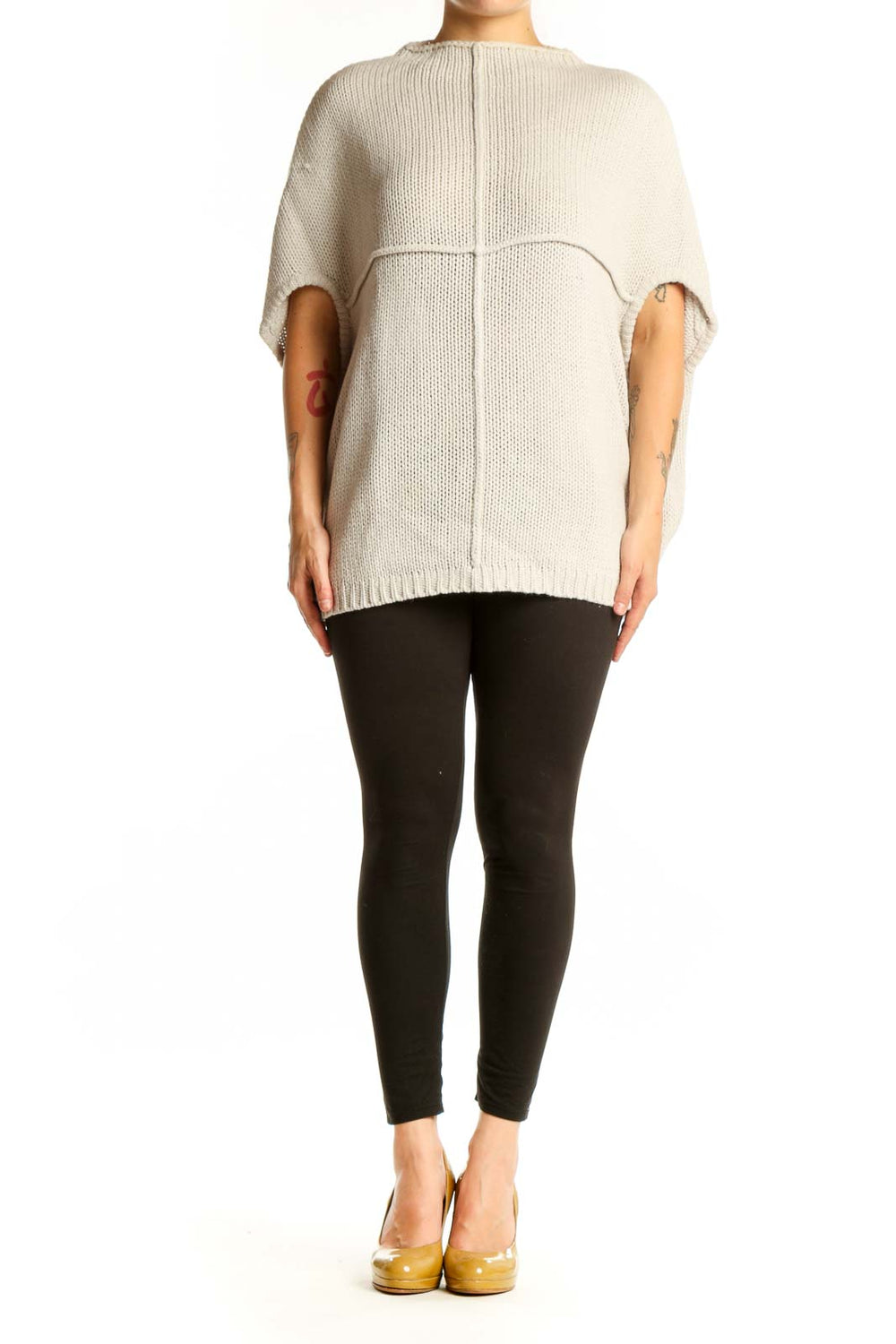 Cream acrylic knit poncho with cutout sleeves, back view showing ribbed texture and oversized fit