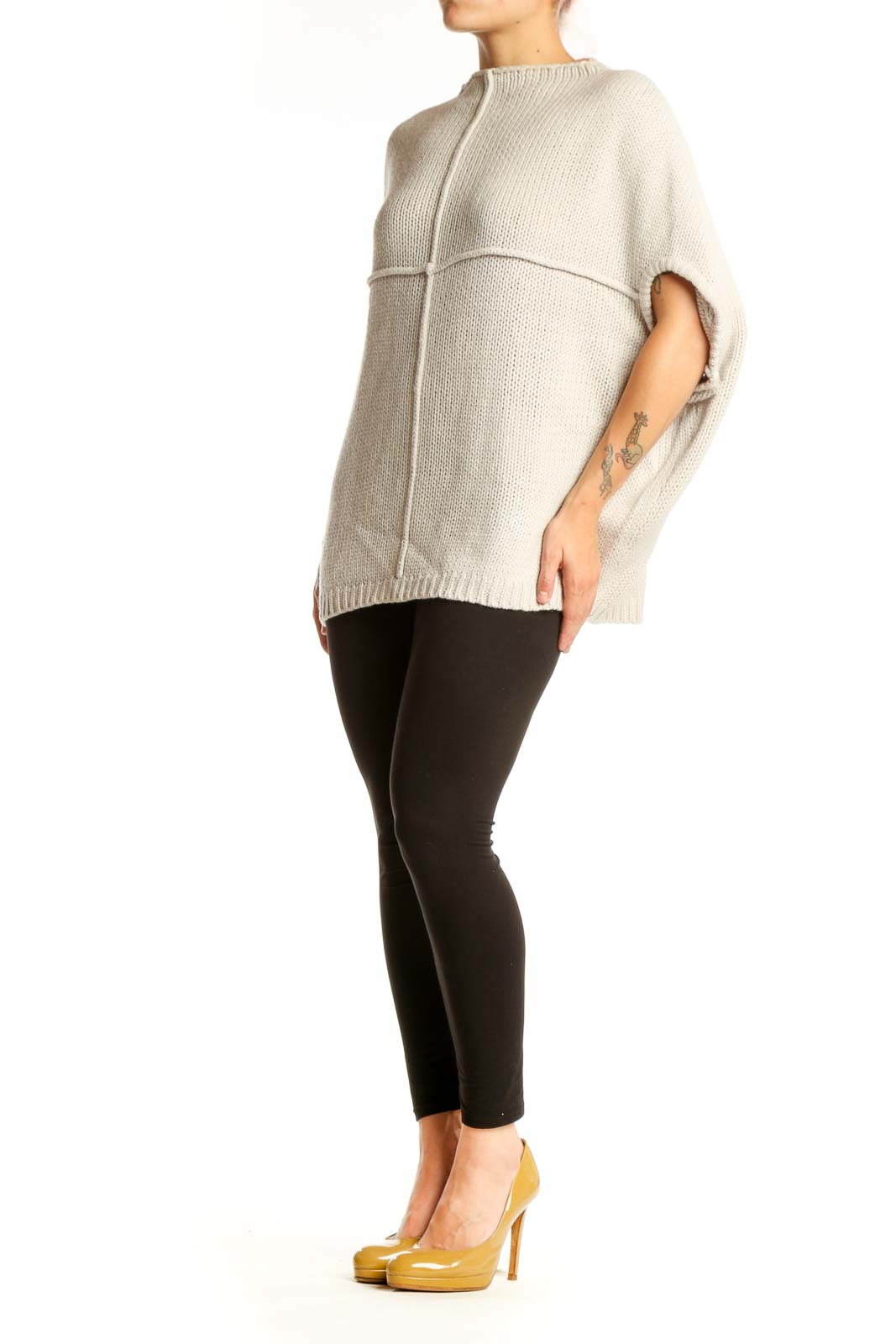 Cream acrylic knit poncho with cutout sleeves, back view showing ribbed texture and oversized fit