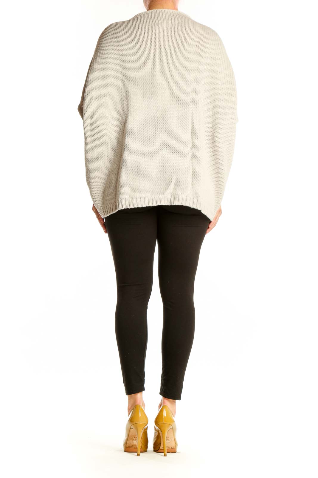 Cream knit poncho with cutout sleeve details, side view displaying relaxed silhouette and modern design