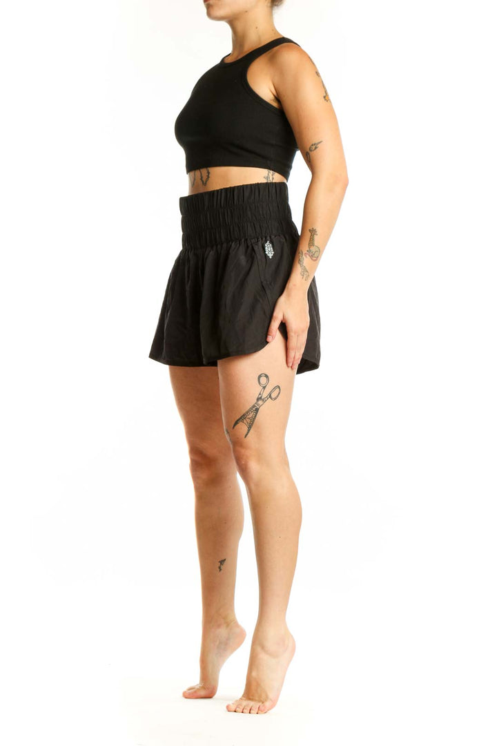 Black athletic shorts with gathered elastic waistband, front view on model