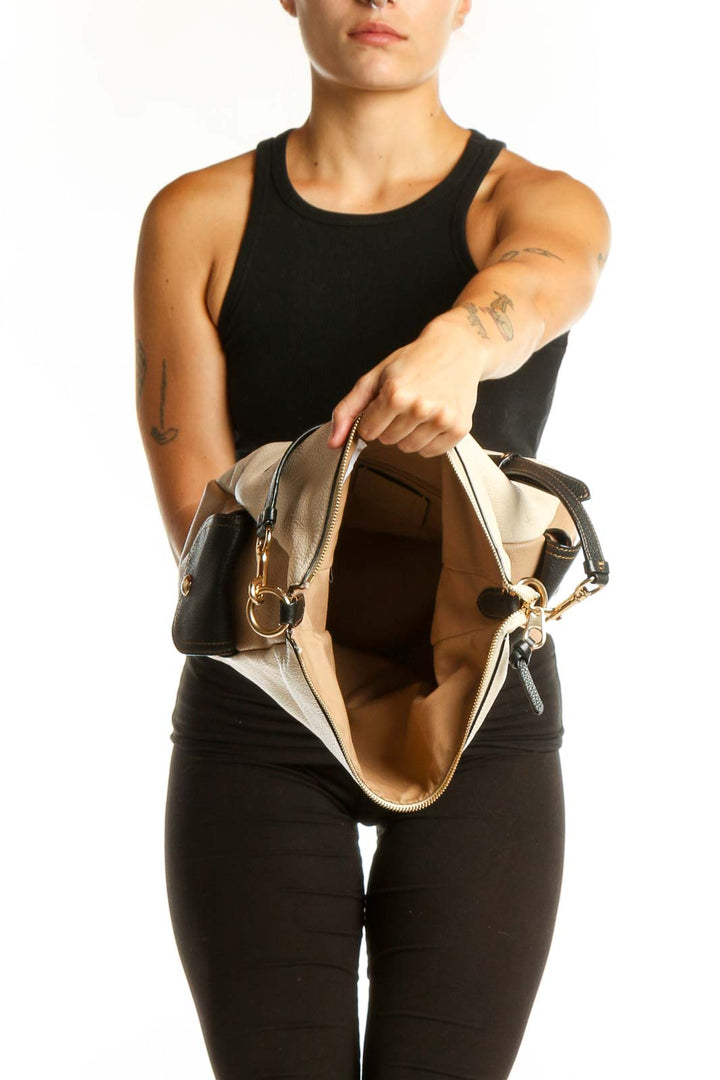 Back view of cream Coach crossbody bag with black leather strap worn across body