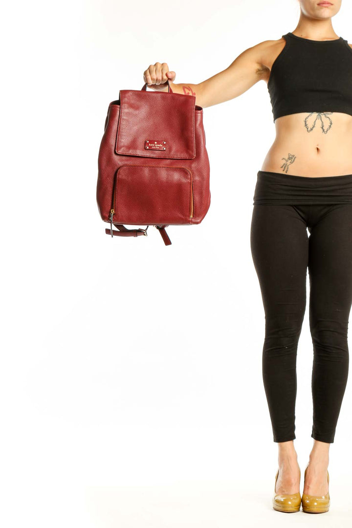 Burgundy leather Kate Spade backpack with top handle and front pocket, displayed from front view