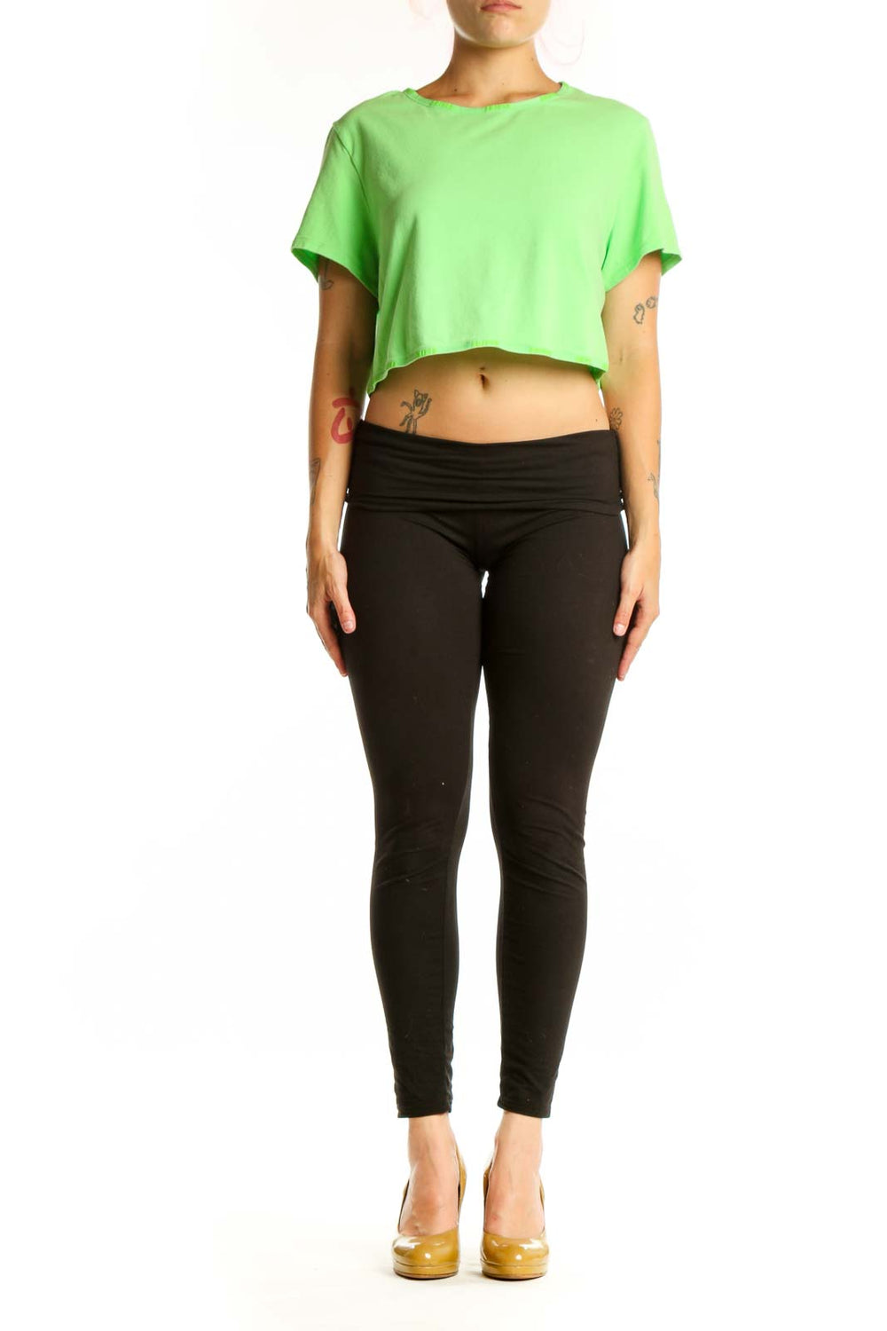 Woman wearing vibrant green cropped short sleeve t-shirt by Skims, paired with black leggings, front view