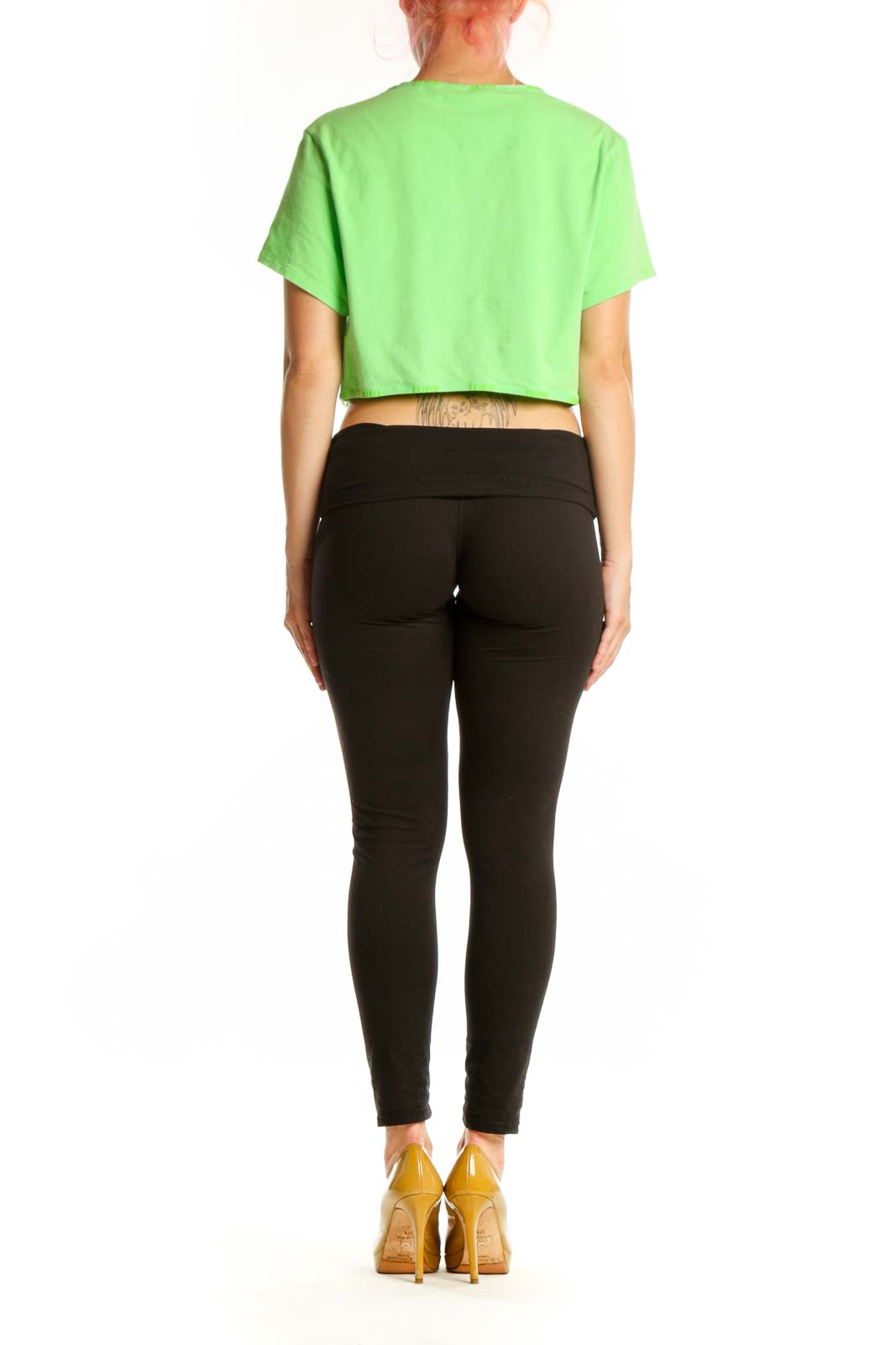 Back view of woman wearing green cropped t-shirt by Skims with black fitted leggings
