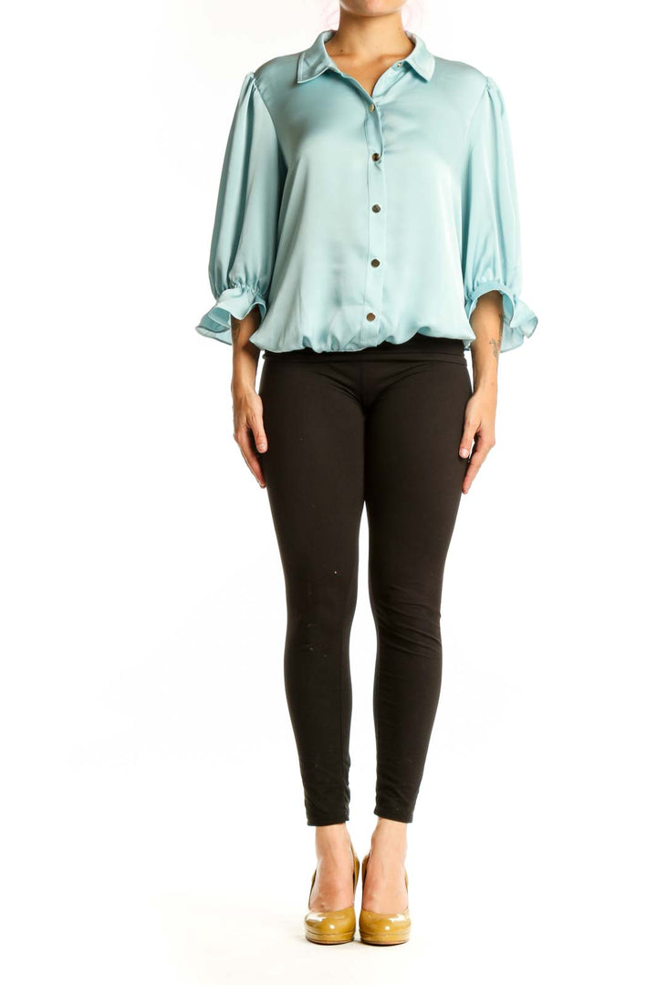 Front view of pale blue puff sleeve button-up blouse with rolled cuffs and brown buttons