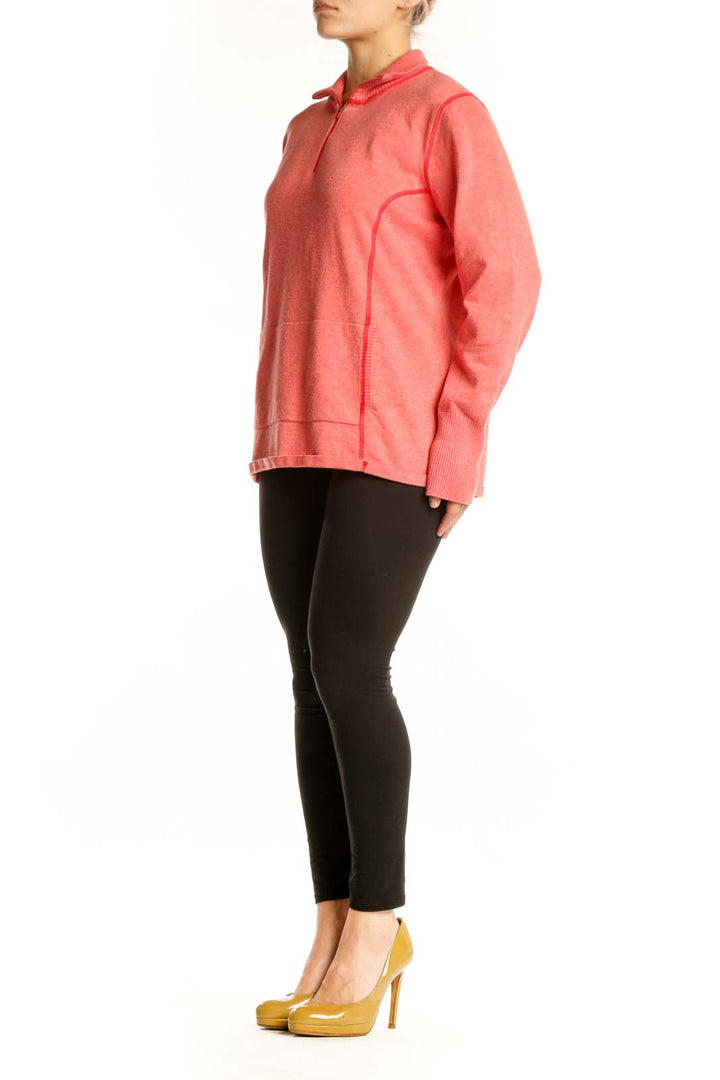 Woman wearing coral Eddie Bauer zip hoodie with quarter-zip design and hood, paired with black leggings