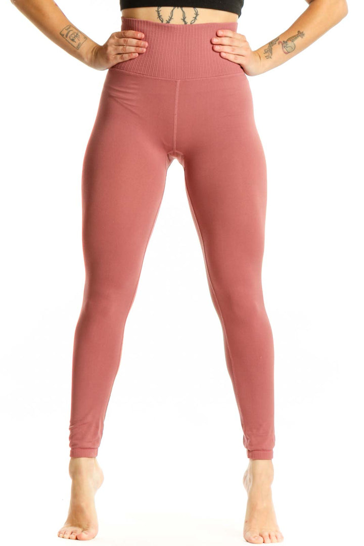Woman wearing pink high-waist ribbed leggings with black sports bra, front view showing flattering fit and ribbed texture detail