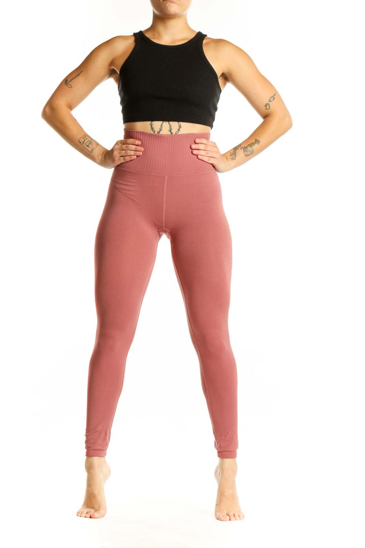Woman wearing pink high-waist ribbed leggings with black sports bra, front view showing flattering fit and ribbed texture detail