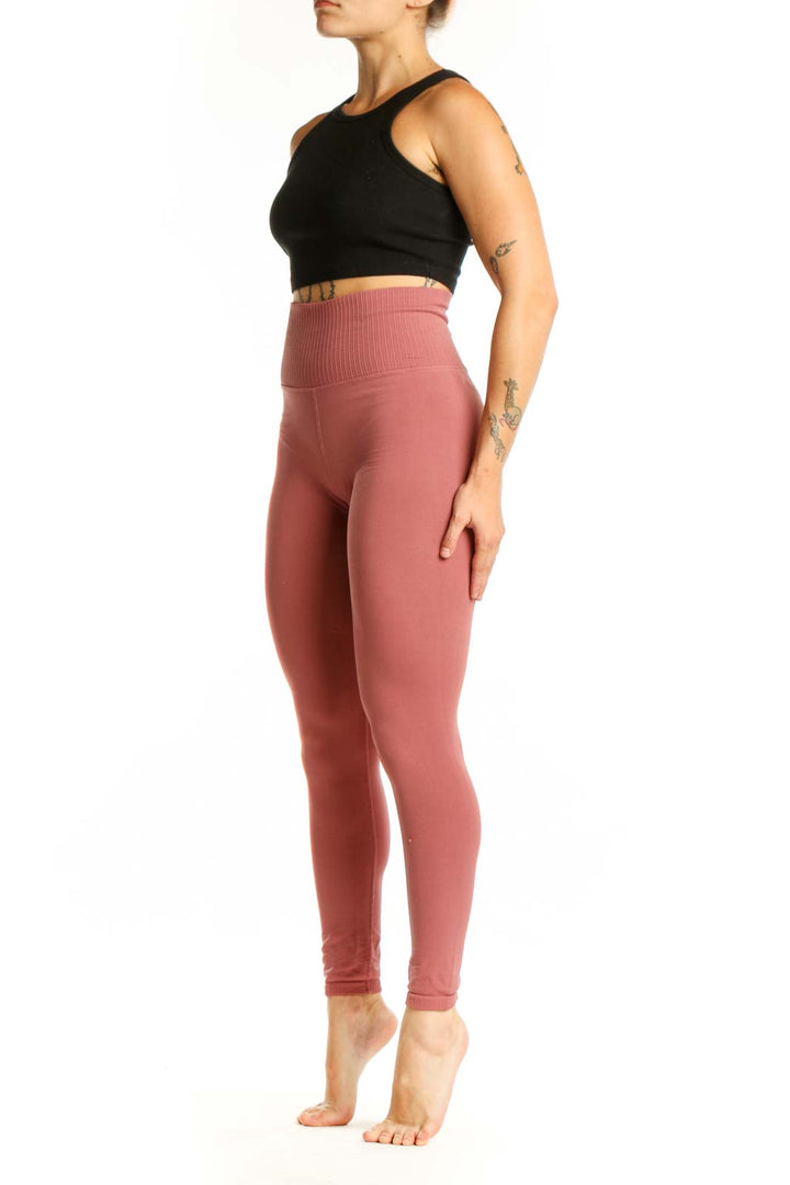 Woman wearing pink high-waist ribbed leggings with black sports bra, front view showing flattering fit and ribbed texture detail