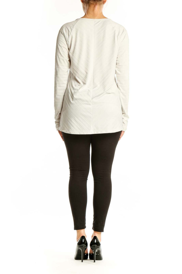 Cream long sleeve athletic top with side vents, back view on model
