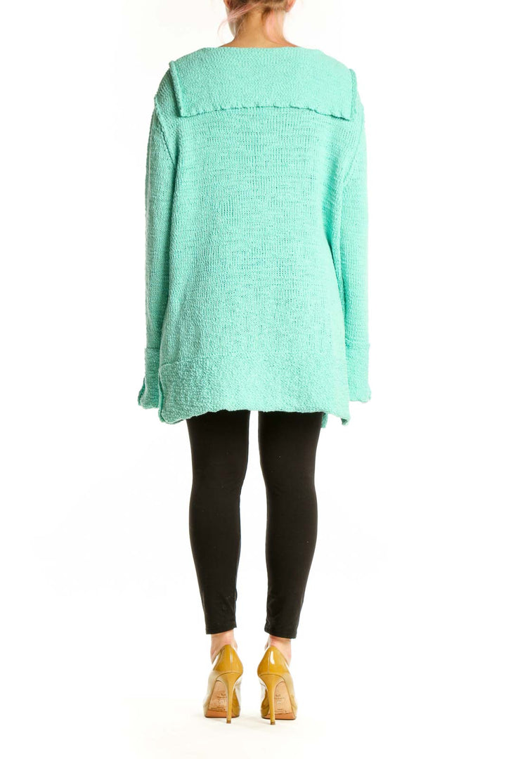 Back view of mint green hooded knit sweater showing relaxed silhouette and rolled cuffs