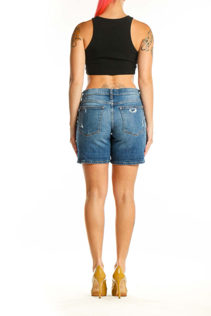 Back view of blue denim shorts showing distressed rip detail on thigh and classic denim construction