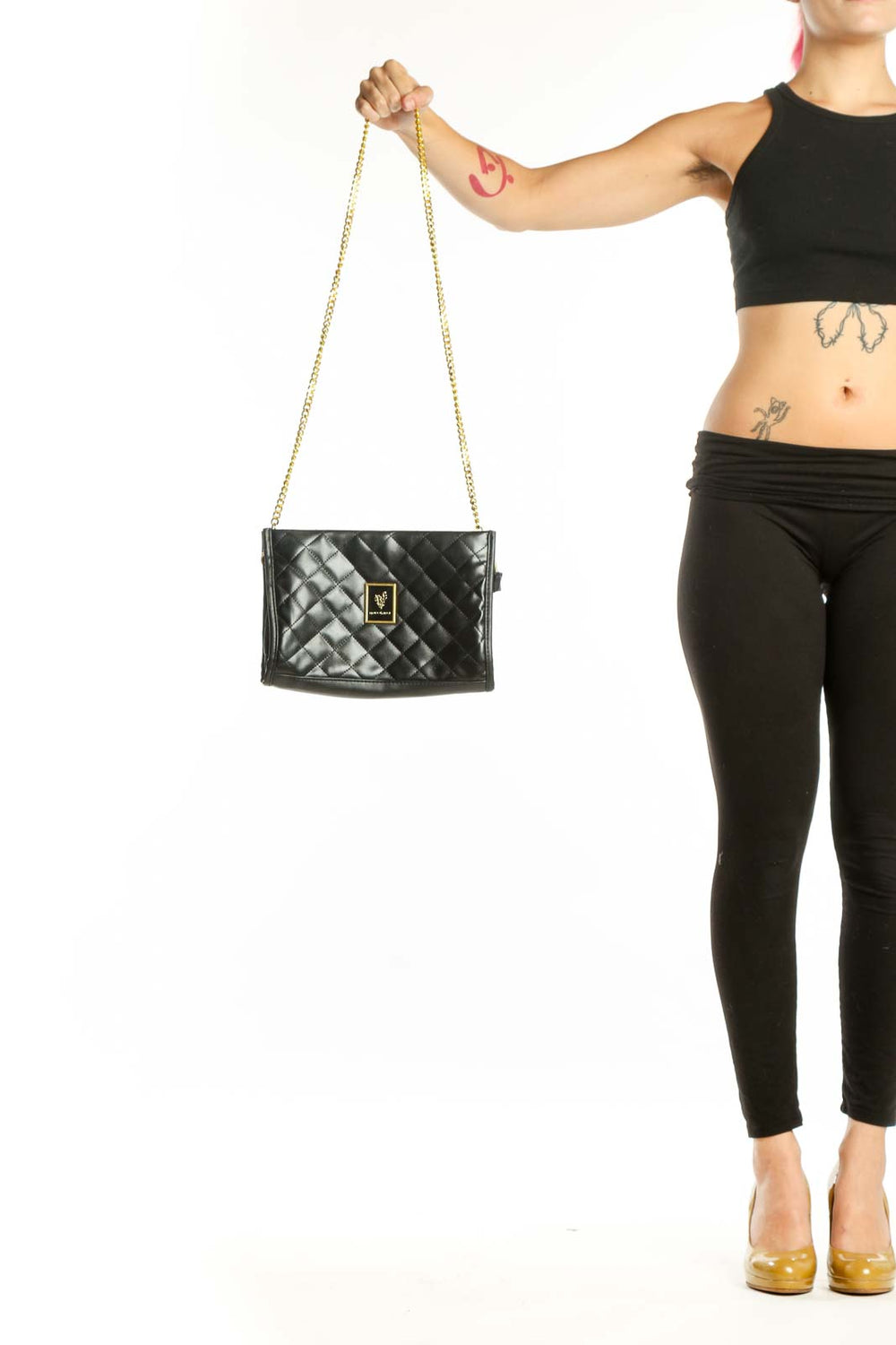 Black quilted PVC crossbody bag with gold chain strap and logo plaque, held in hand