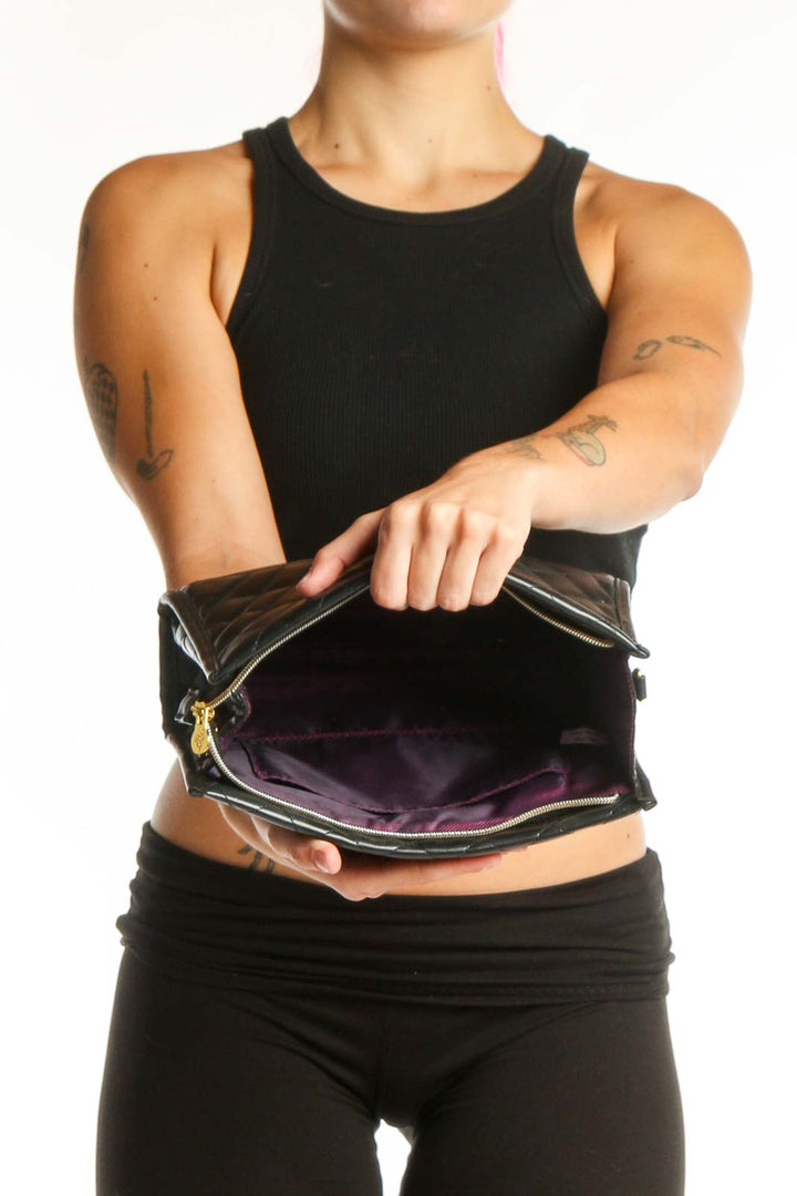 Black quilted crossbody bag worn on shoulder, showing side profile and adjustable gold chain strap