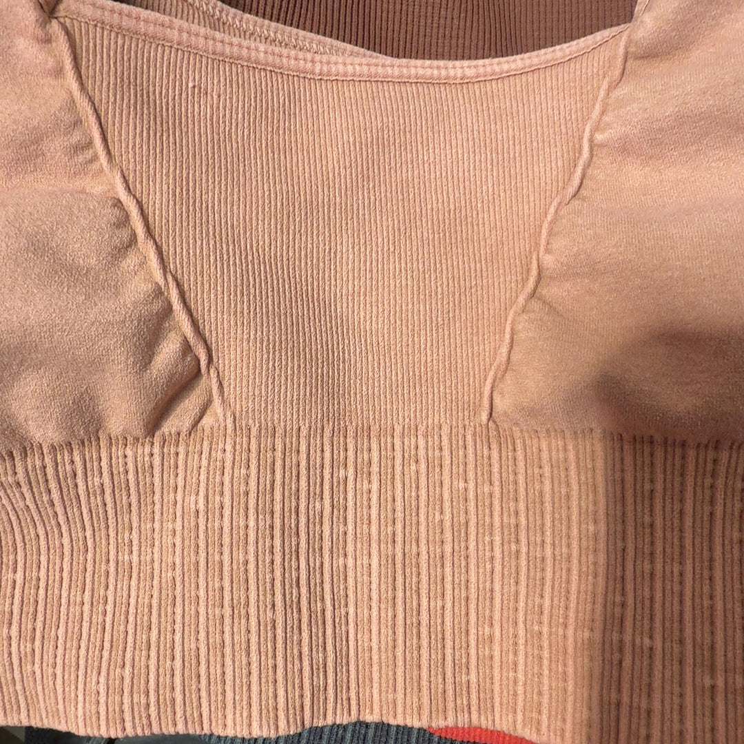 Beige ribbed crop top sports bra back view on model, showing fitted silhouette and ribbed texture detail