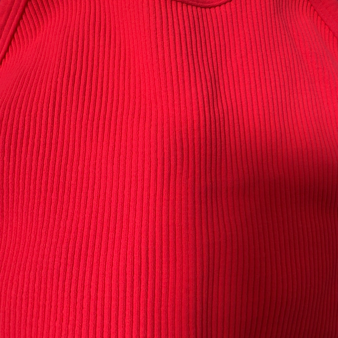 Woman wearing pink ribbed crop tank top with racerback design and black leggings, back view