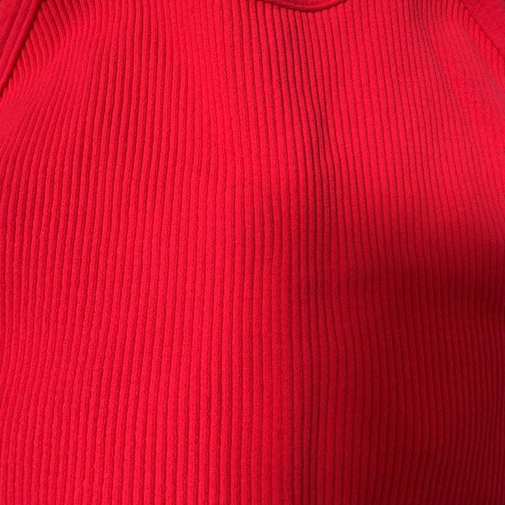 Woman wearing pink ribbed crop tank top with racerback design and black leggings, back view