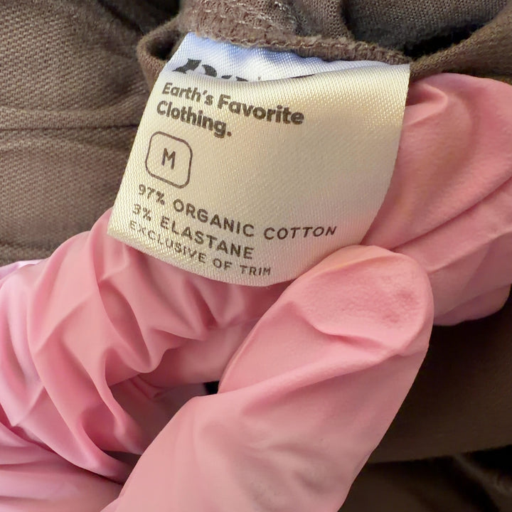 Tag view of brown organic cotton drawstring pants showing relaxed silhouette and functional back pockets