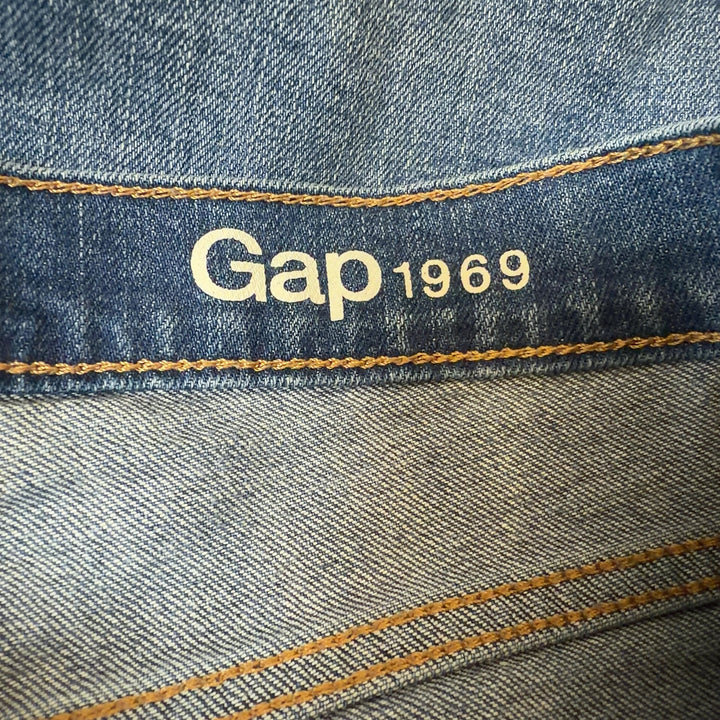 Tag view of blue denim cut-off shorts showing distressed cut-off hem and fit