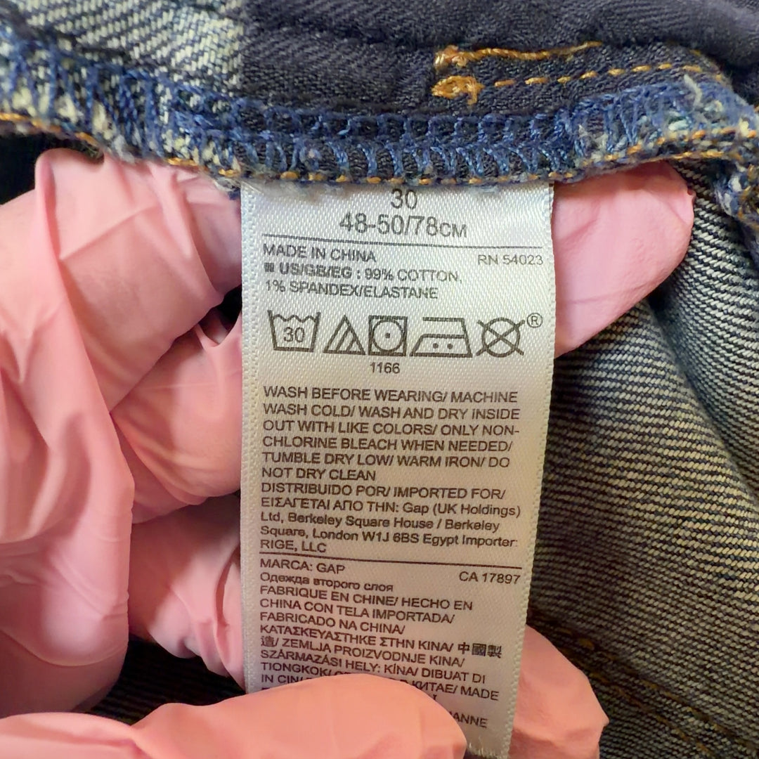 Tag view of blue denim cut-off shorts showing distressed cut-off hem and fit