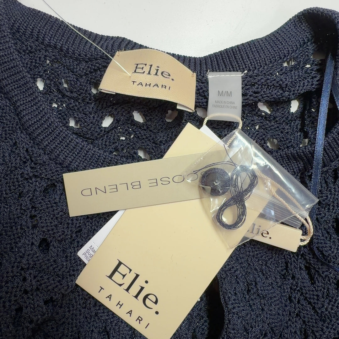 Tag view of black openwork knit cardigan showing intricate eyelet pattern and fitted silhouette