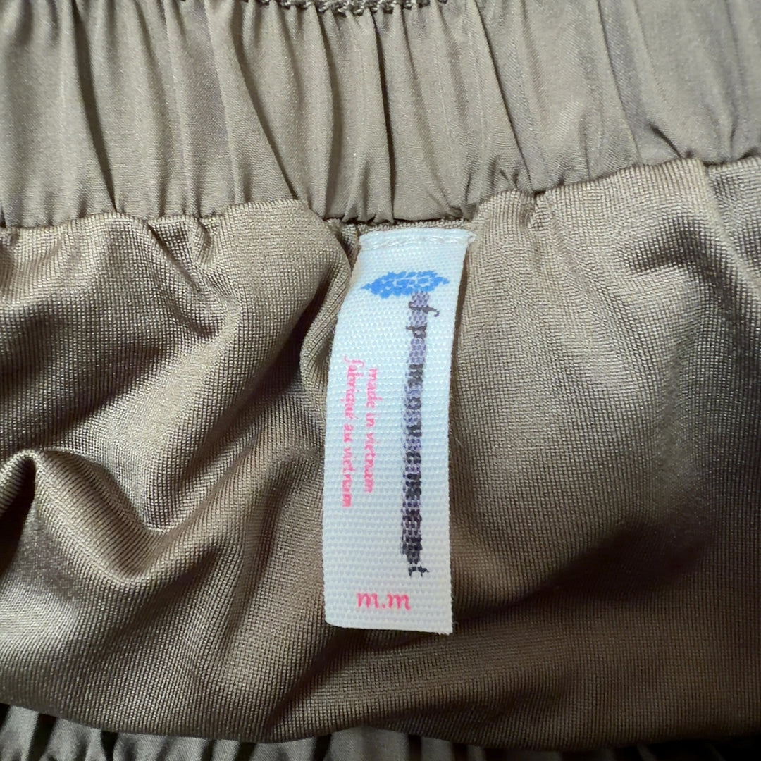 Olive green ruched athletic skirt back view with side pockets, paired with black sports bra