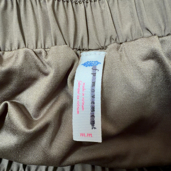 Olive green ruched athletic skirt back view with side pockets, paired with black sports bra