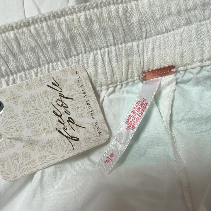 Tag view of cream track pants with mint green side stripe and functional back pocket