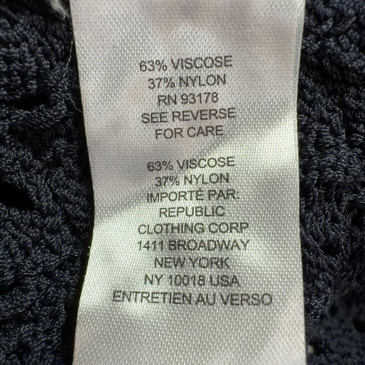Tag view of black openwork knit cardigan showing intricate eyelet pattern and fitted silhouette
