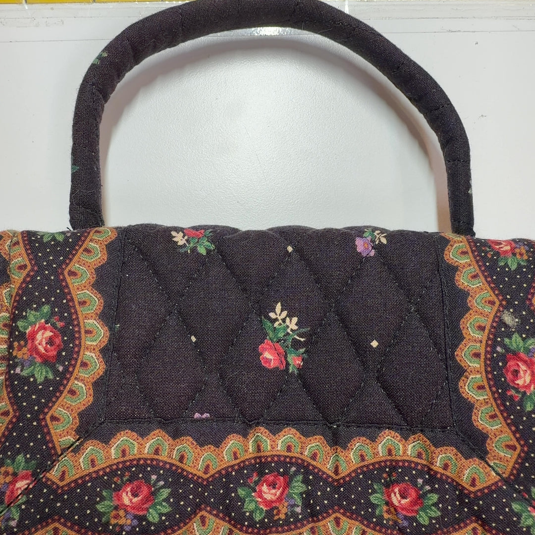 Tag view of brown quilted Vera Bradley satchel displaying floral pattern and embroidered details