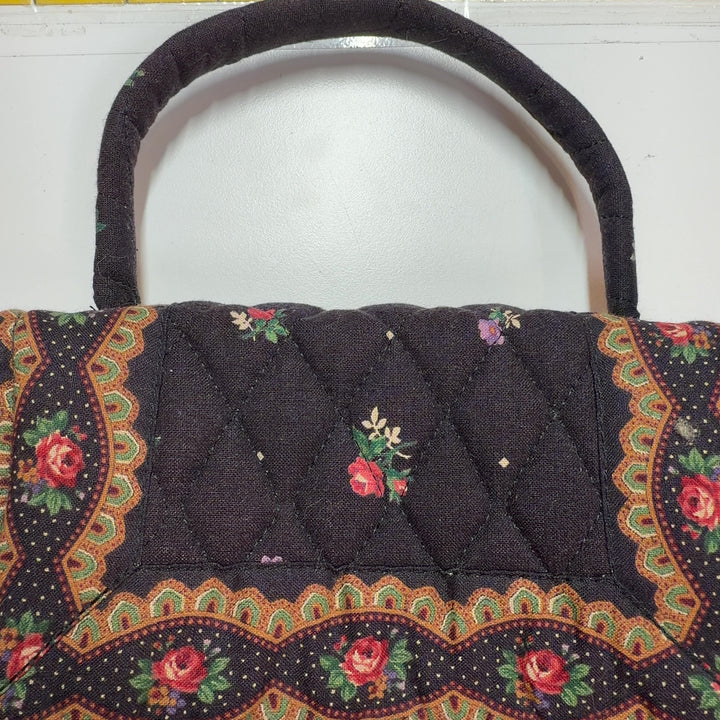 Tag view of brown quilted Vera Bradley satchel displaying floral pattern and embroidered details
