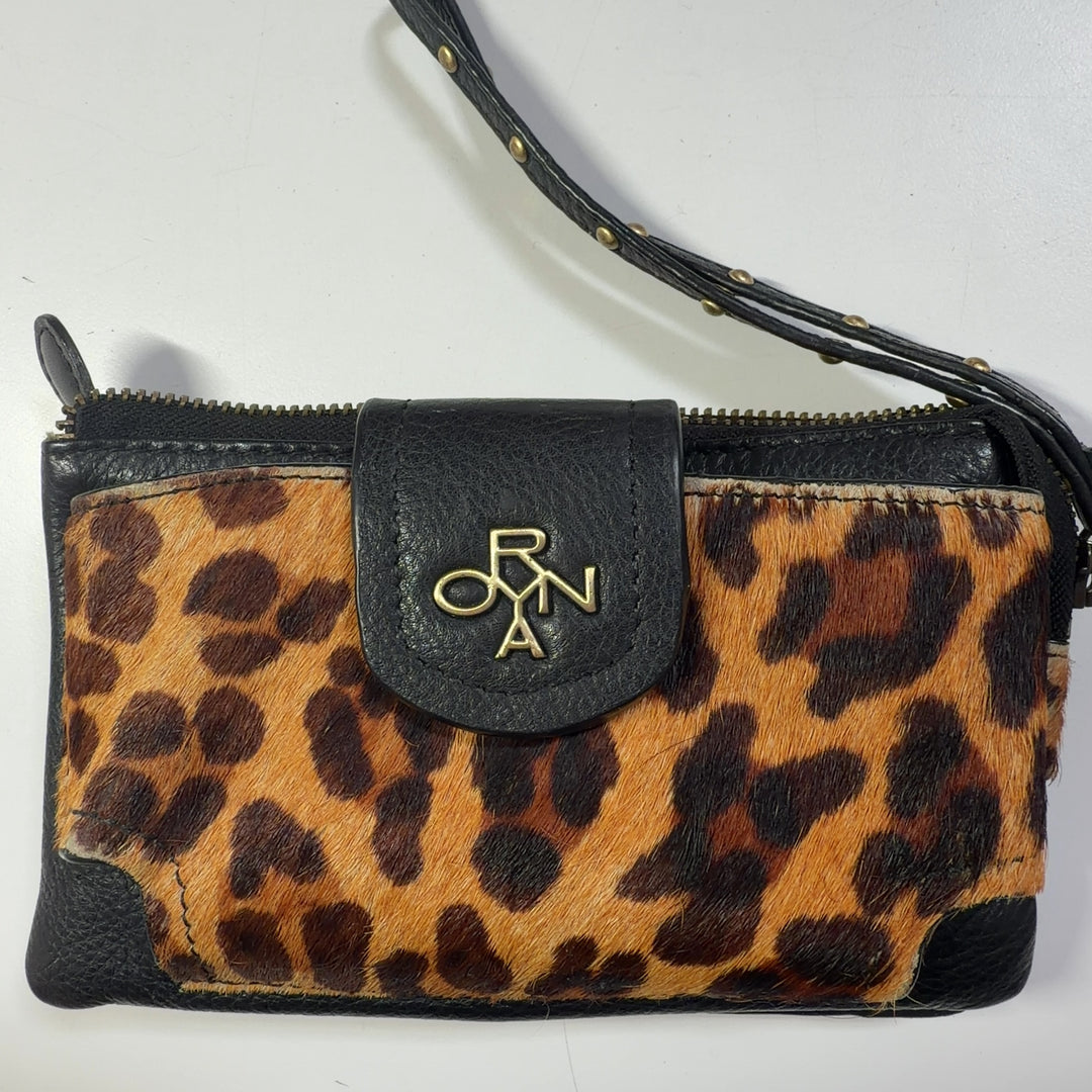 ORYAN leopard print clutch with wristlet strap styled as a fashion accessory worn with black outfit