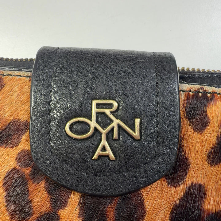 ORYAN leopard print clutch with wristlet strap styled as a fashion accessory worn with black outfit