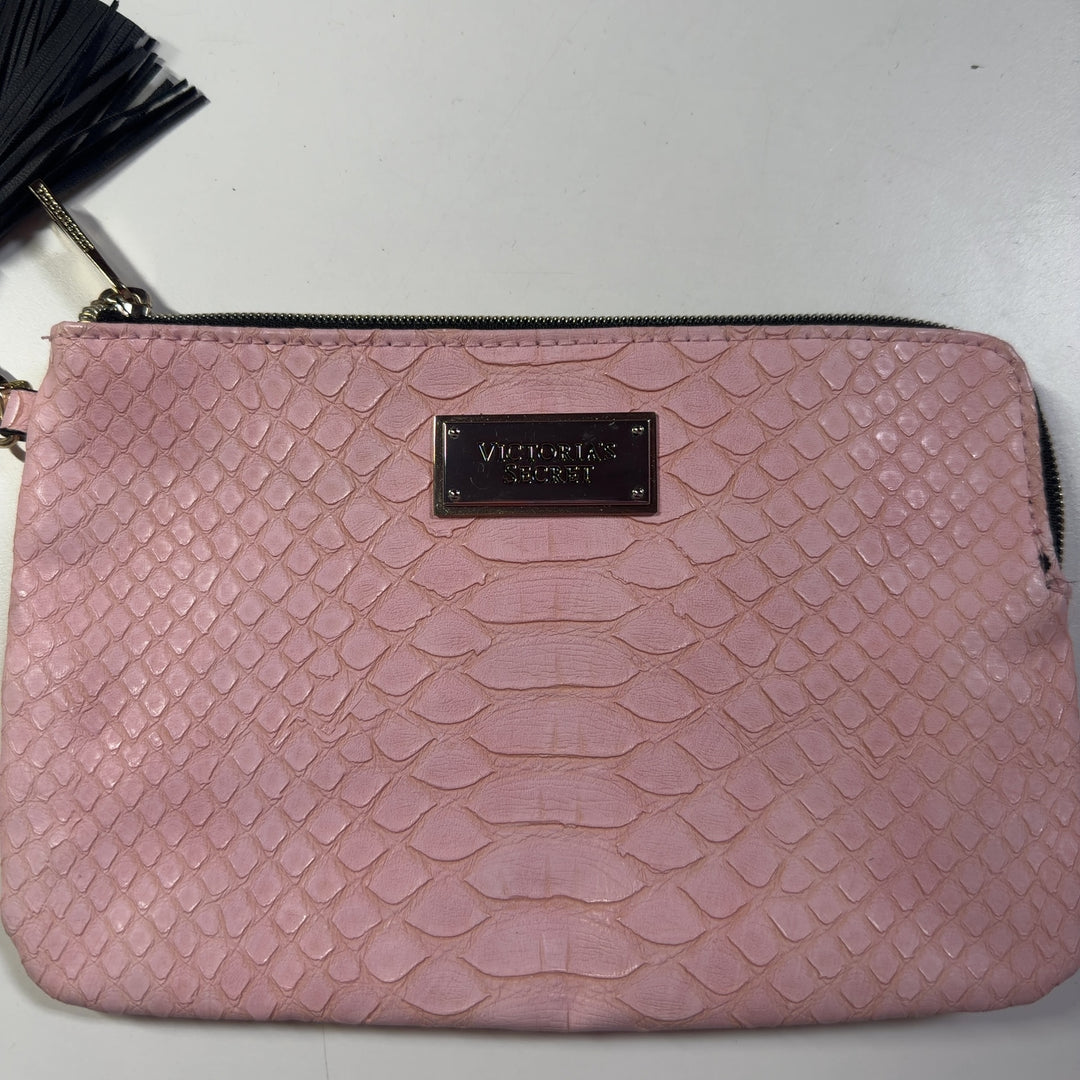 Tag view of pink quilted clutch being held, showing tassel detail and metal nameplate