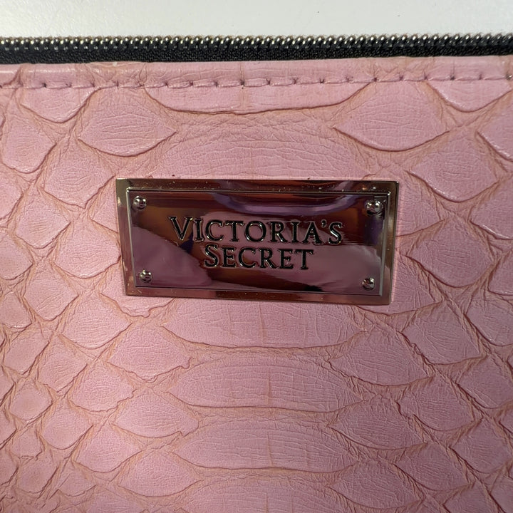 Tag view of pink quilted clutch being held, showing tassel detail and metal nameplate