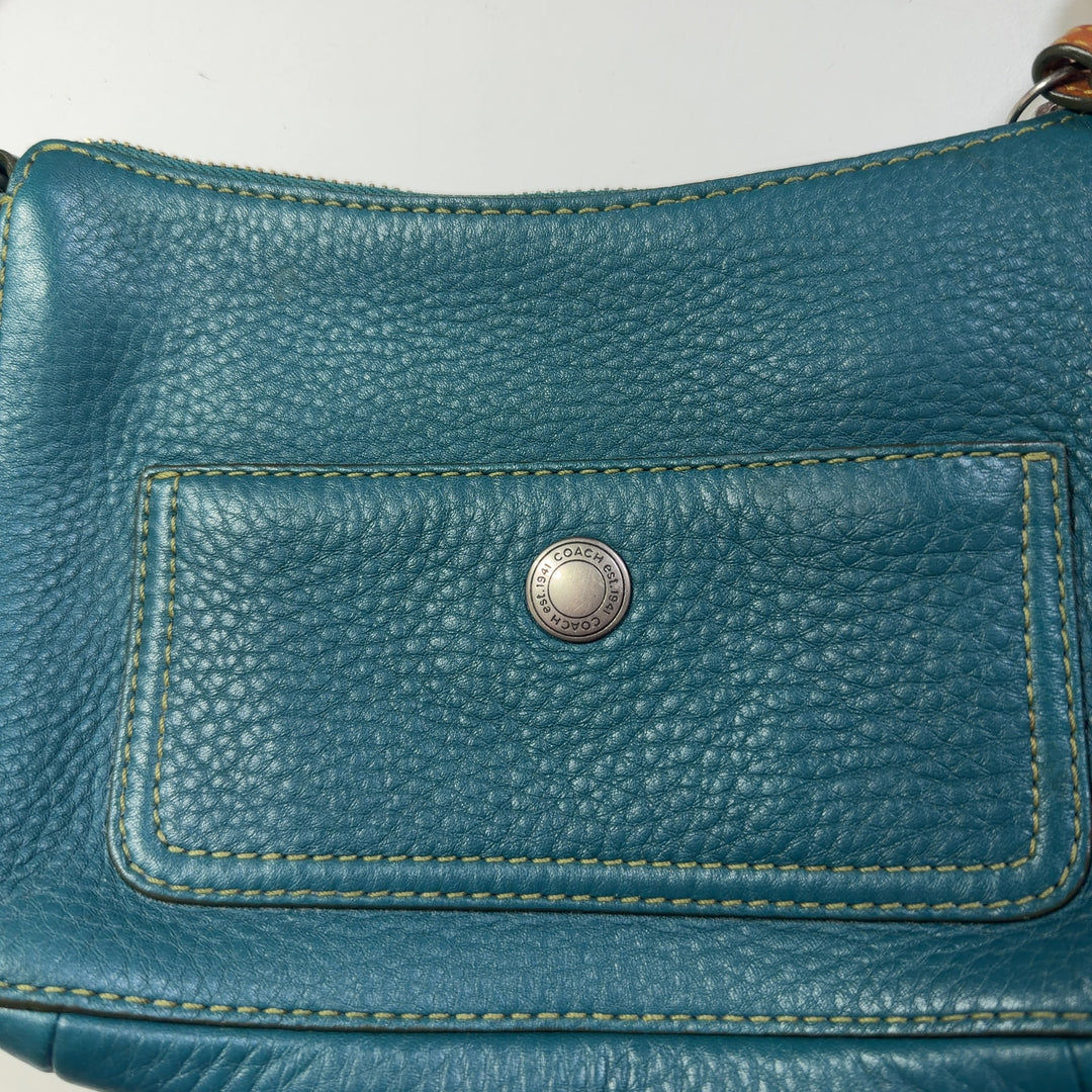Teal Coach shoulder bag worn as crossbody style, showing back view and strap detail