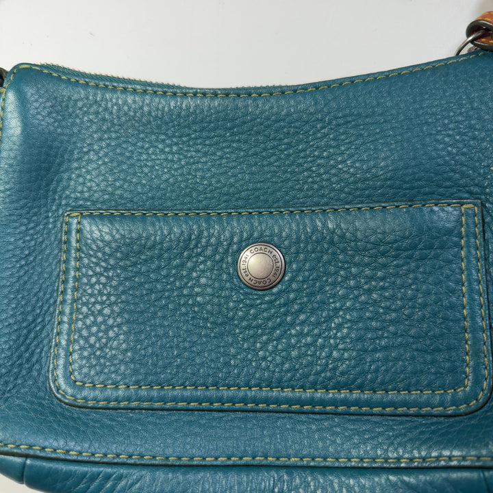 Teal Coach shoulder bag worn as crossbody style, showing back view and strap detail