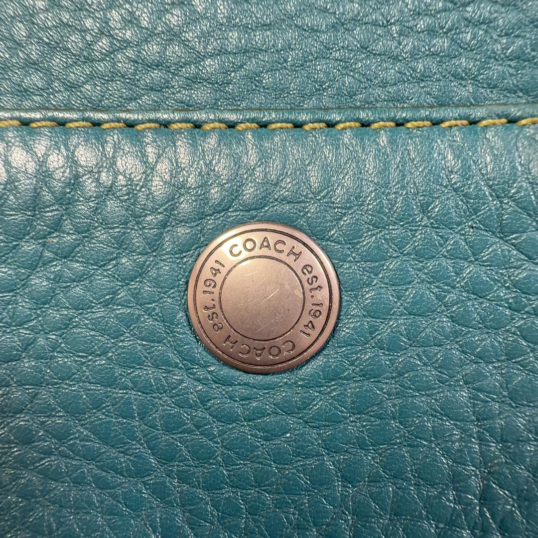 Teal Coach shoulder bag worn as crossbody style, showing back view and strap detail