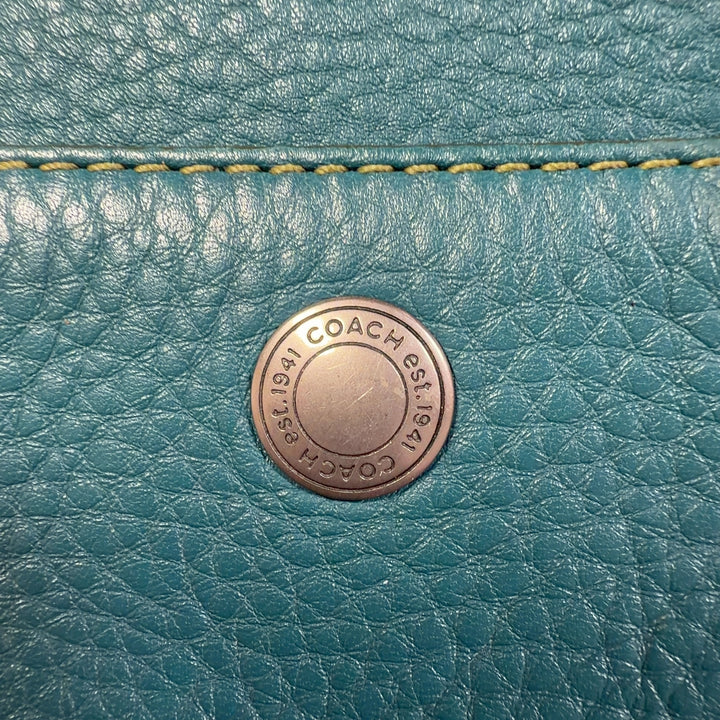 Teal Coach shoulder bag worn as crossbody style, showing back view and strap detail