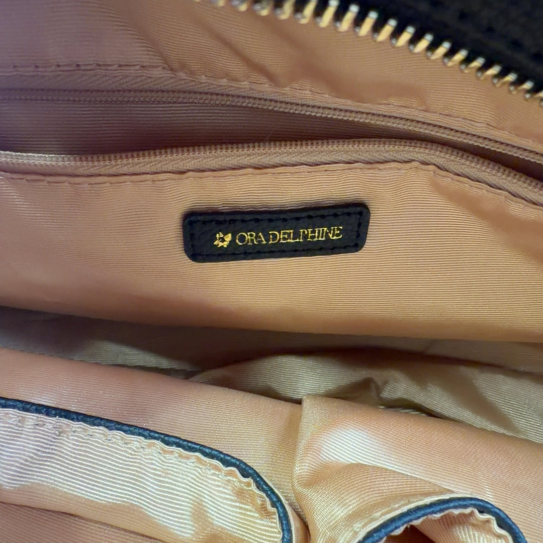 Black leather satchel bag worn on shoulder, displaying back view and structured silhouette with red leather accent