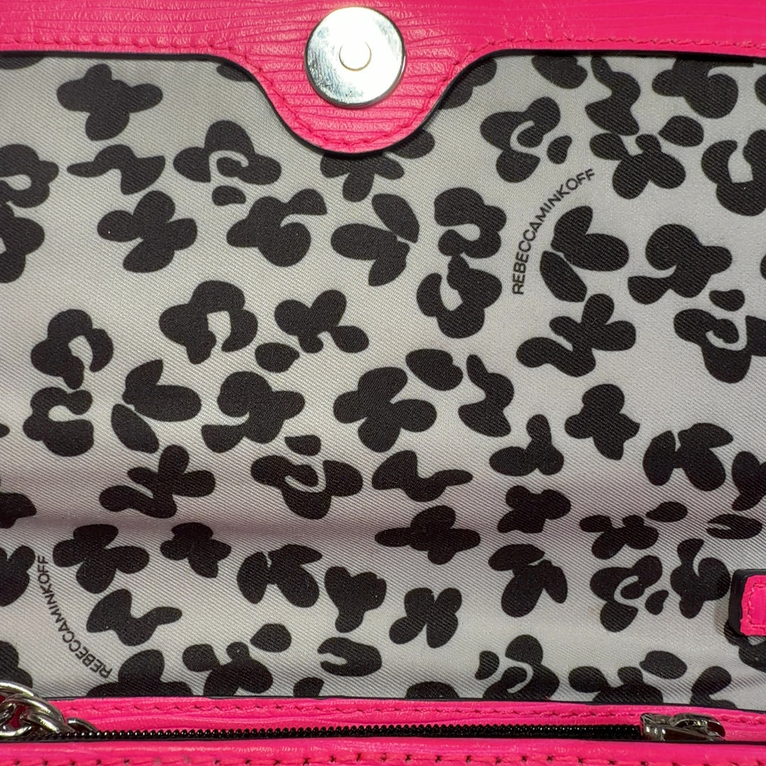 Tag view of pink Rebecca Minkoff crossbody bag worn on shoulder with adjustable chain strap