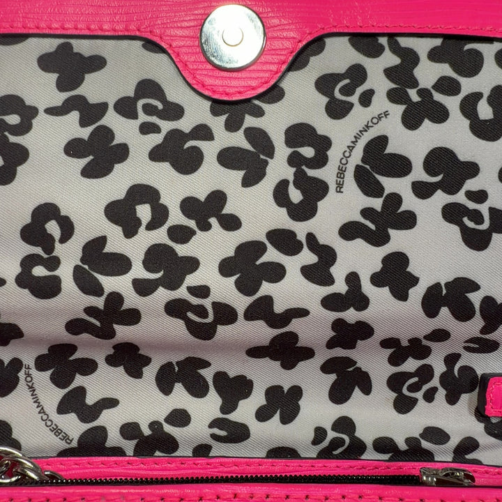 Tag view of pink Rebecca Minkoff crossbody bag worn on shoulder with adjustable chain strap