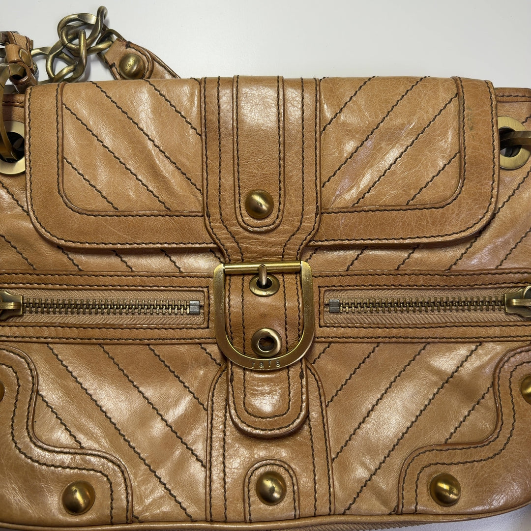 Tag view of tan quilted leather shoulder bag worn as crossbody style with chain strap
