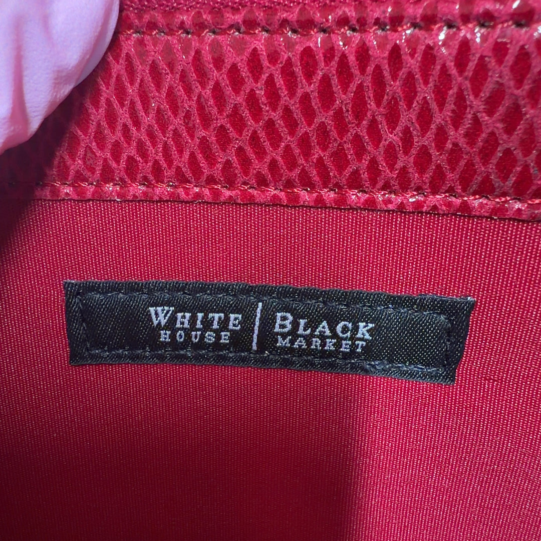 Red leather clutch styled with black outfit, showing back view and gold hardware detail