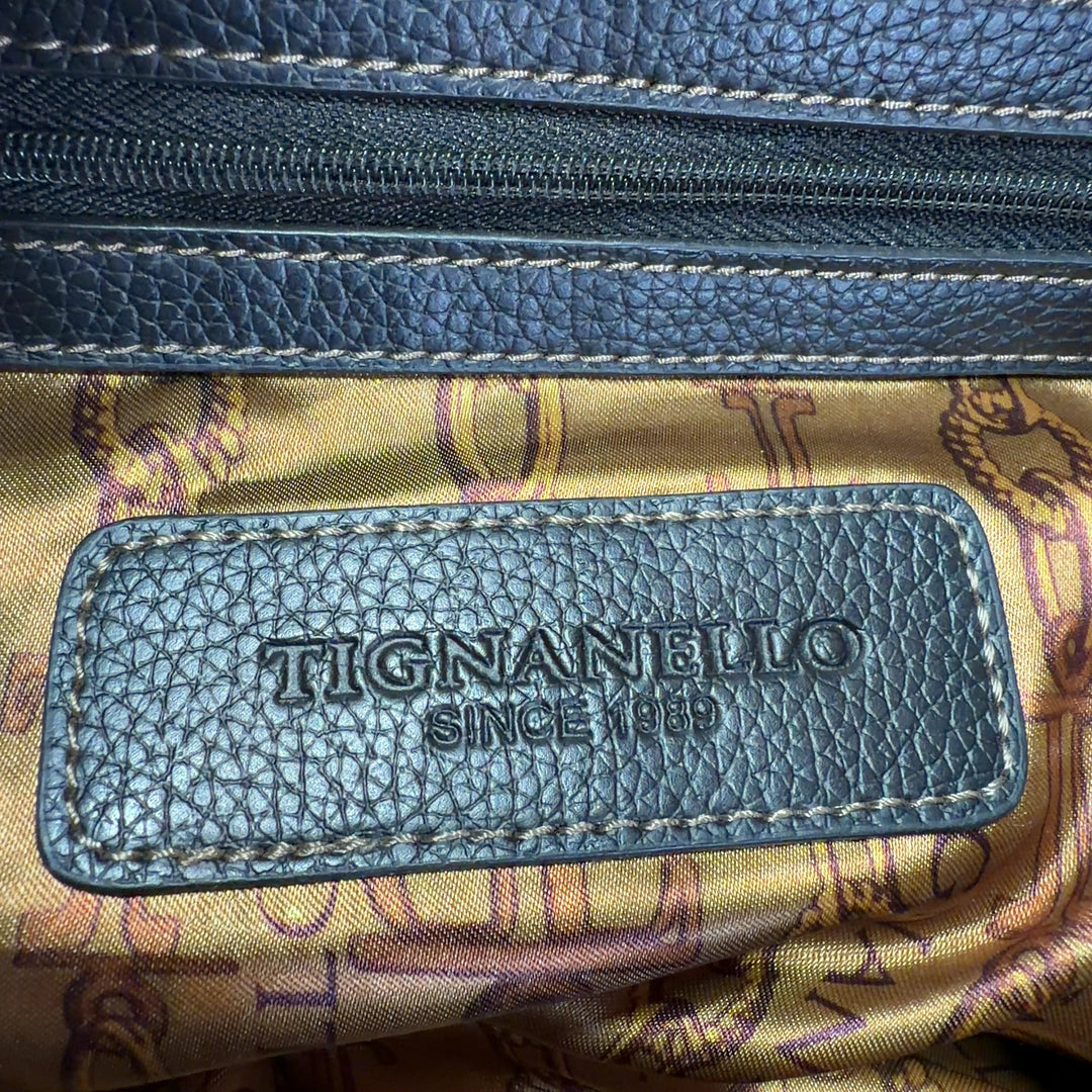 Tag view of black leather Tignanello shoulder tote bag worn on shoulder showing spacious interior and quality construction