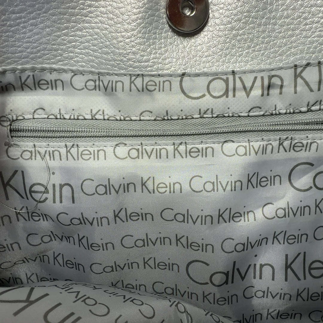 Beige linen Calvin Klein tote bag with white handles and trim, back view on model
