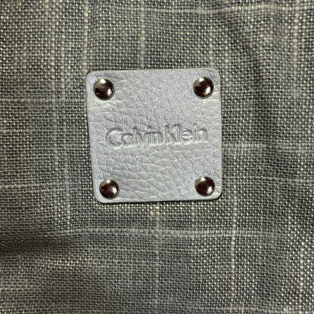 Beige linen Calvin Klein tote bag with white handles and trim, back view on model