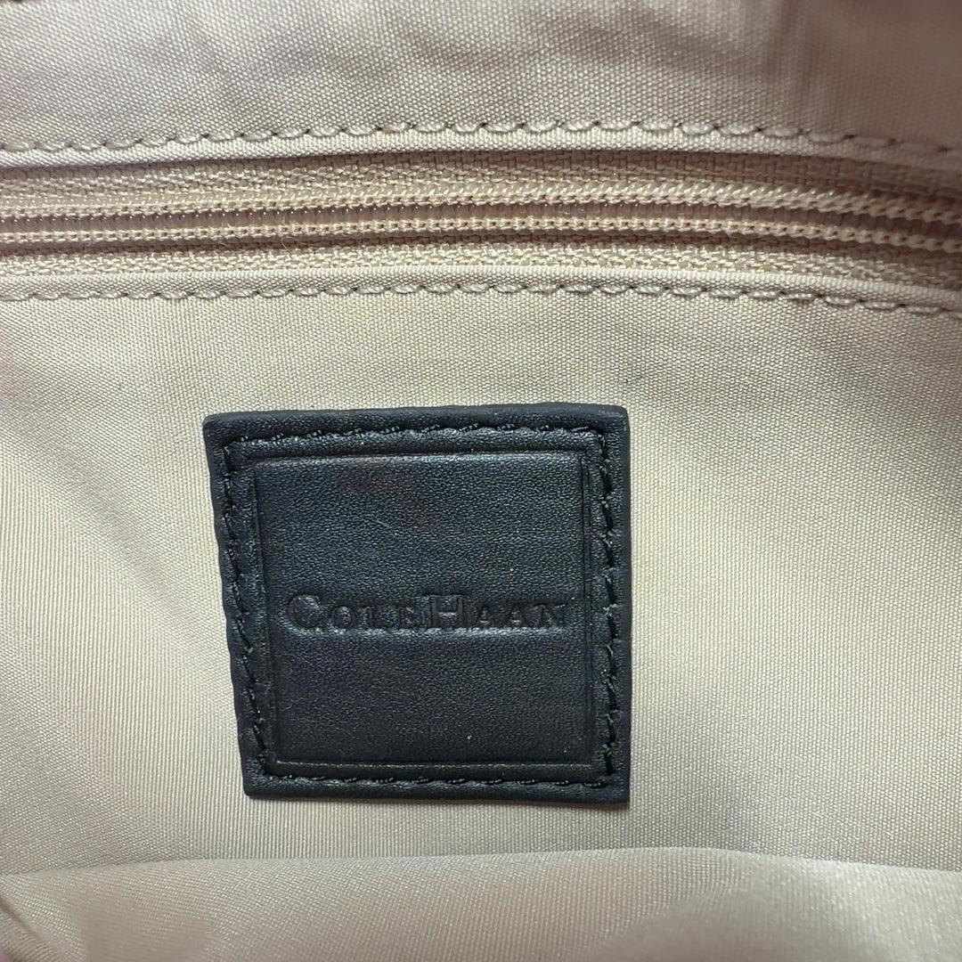 Black studded clutch worn as shoulder bag, displaying back view and dual shoulder straps
