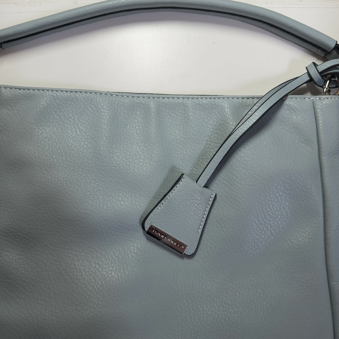 Tag view of sage green David Jones Paris crossbody bag worn on shoulder, showing structured silhouette and strap adjustment